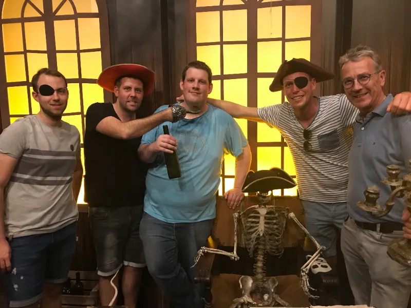 Fünf Kollegen, teils mit Piratenhut und Augenklappe, davor ein Skelett