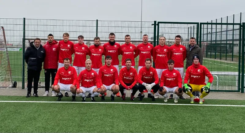 Fußballmannschaft in roten Trikots, zwei Reihen auf einem Kunstrasenplatz