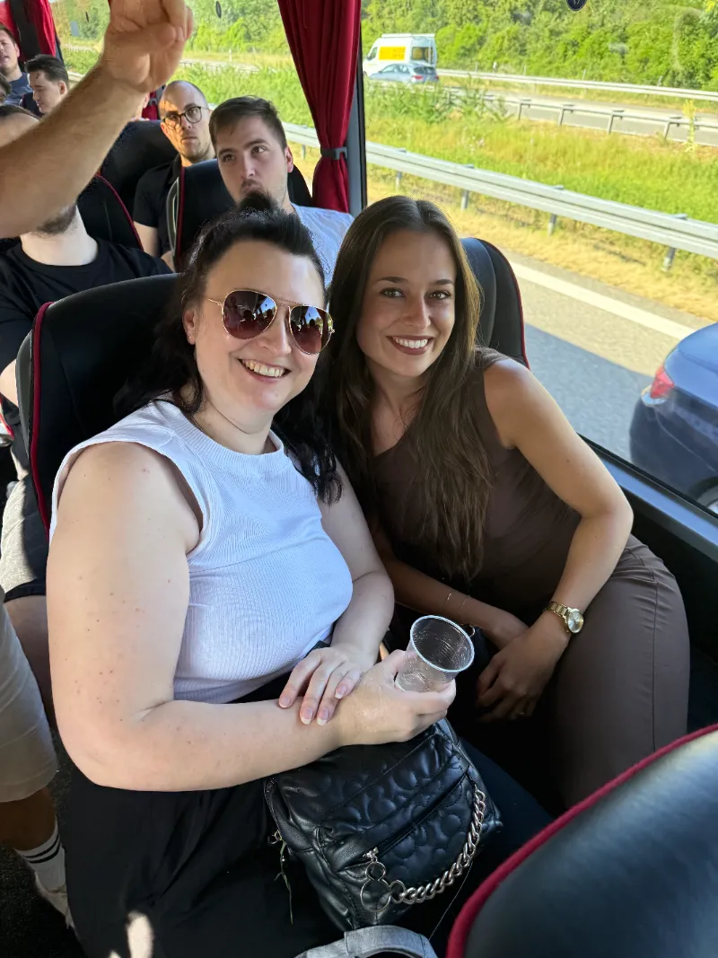 Zwei Kolleginnen nebeneinander im Reisebus, hinter dem Fenster eine Autobahn