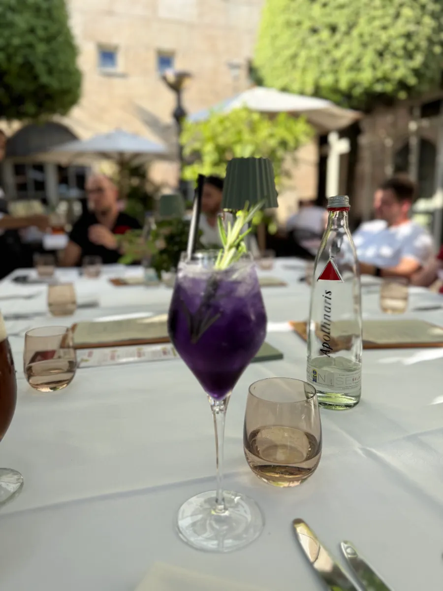 Violettes Getränk mit Kräuterzweig auf einem gedeckten Tisch im Freien