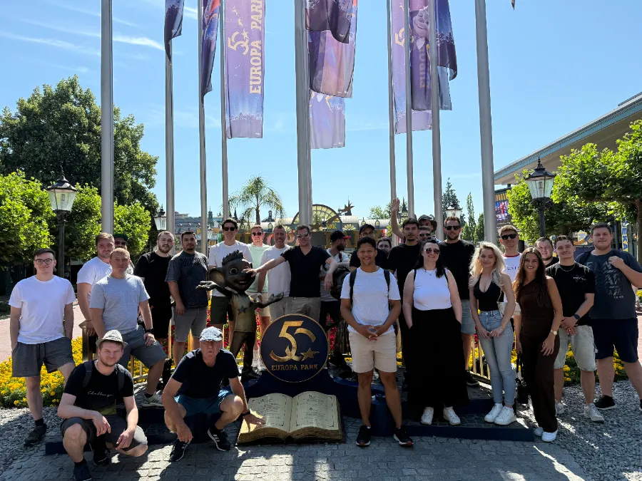 Rund 25 Kolleginnen und Kollegen unter Europa-Park-Fahnen, davor ein 50-Jahre-Emblem