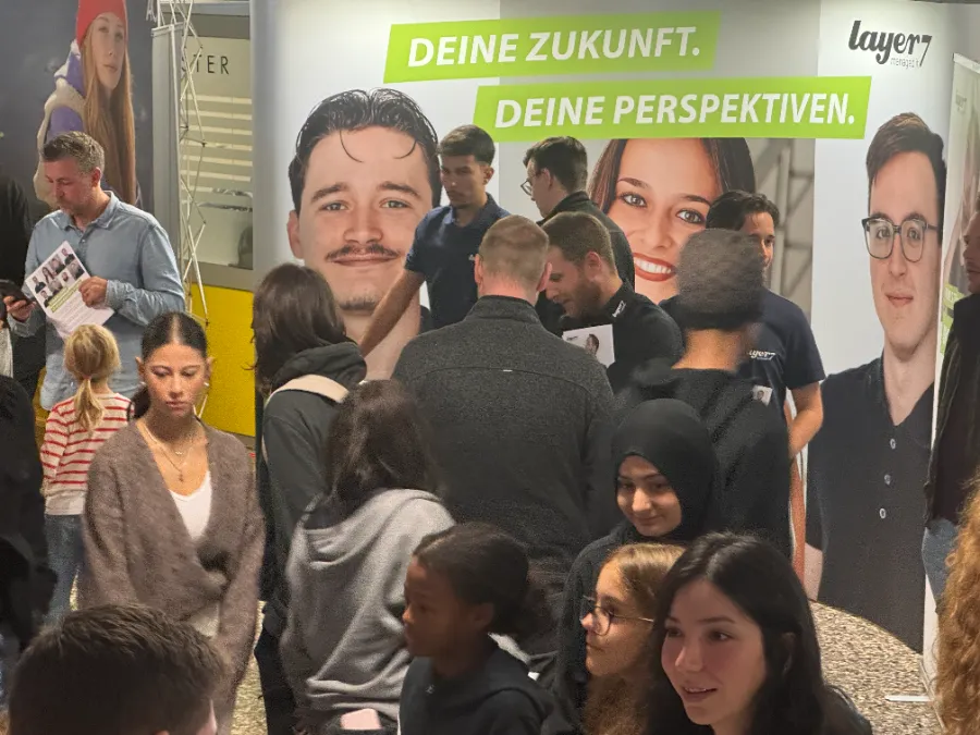 Menschenmenge vor einer layer7-Wand mit dem Schriftzug „Deine Zukunft. Deine Perspektiven.“